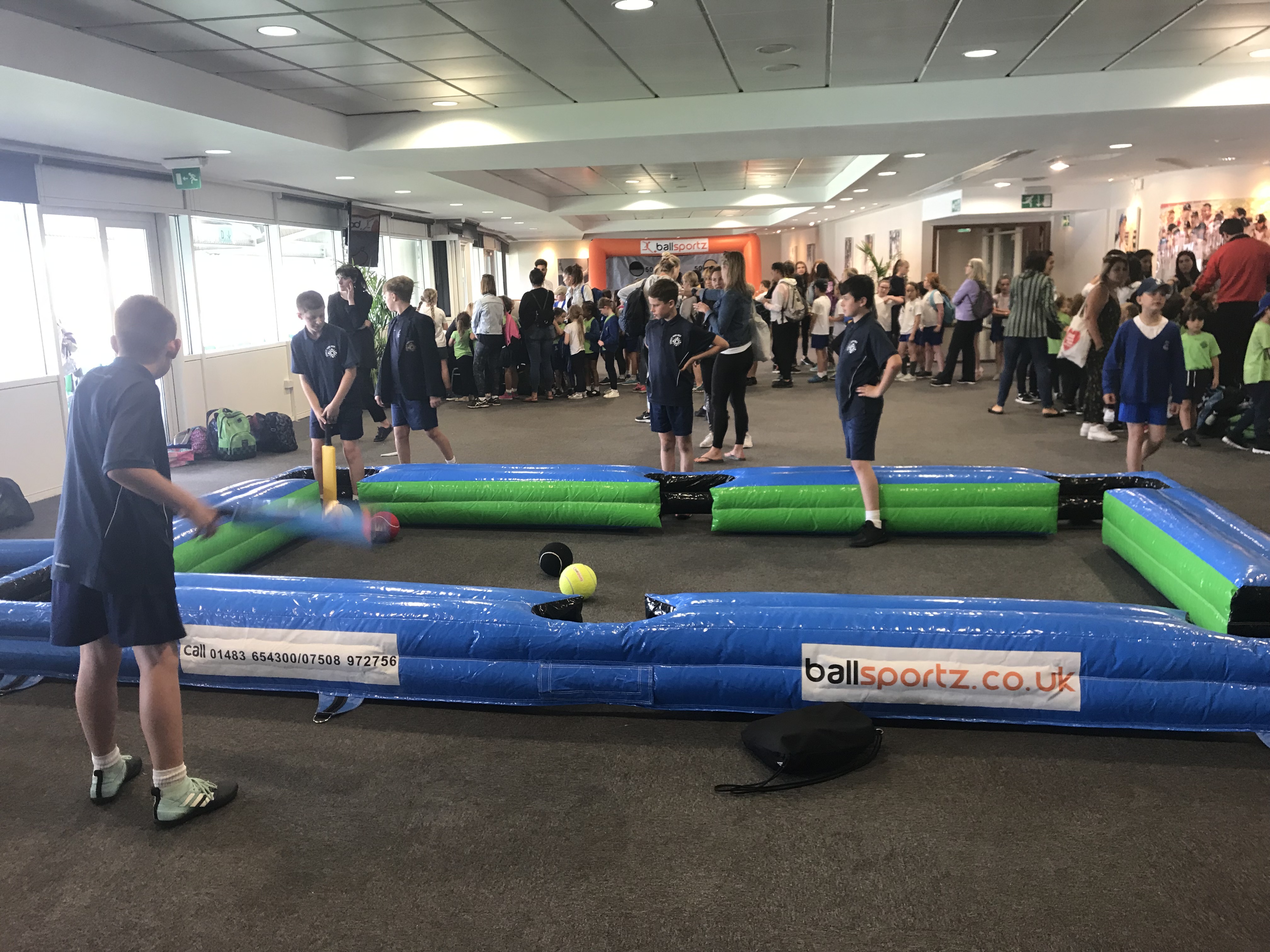 Children play in an indoor arena with inflatable barriers.