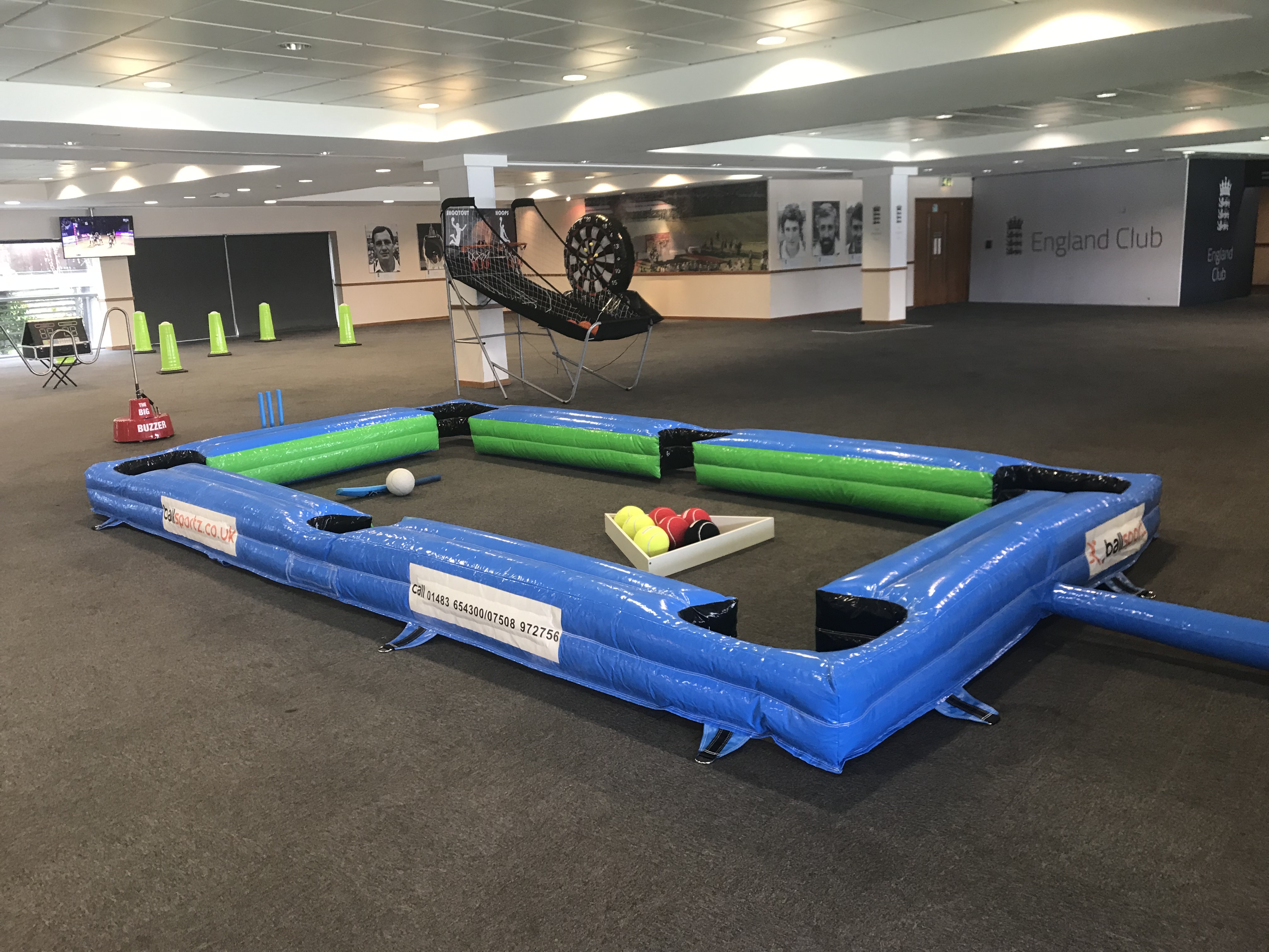 Inflatable pool table with soccer balls and colored foam barriers in an indoor sports area.