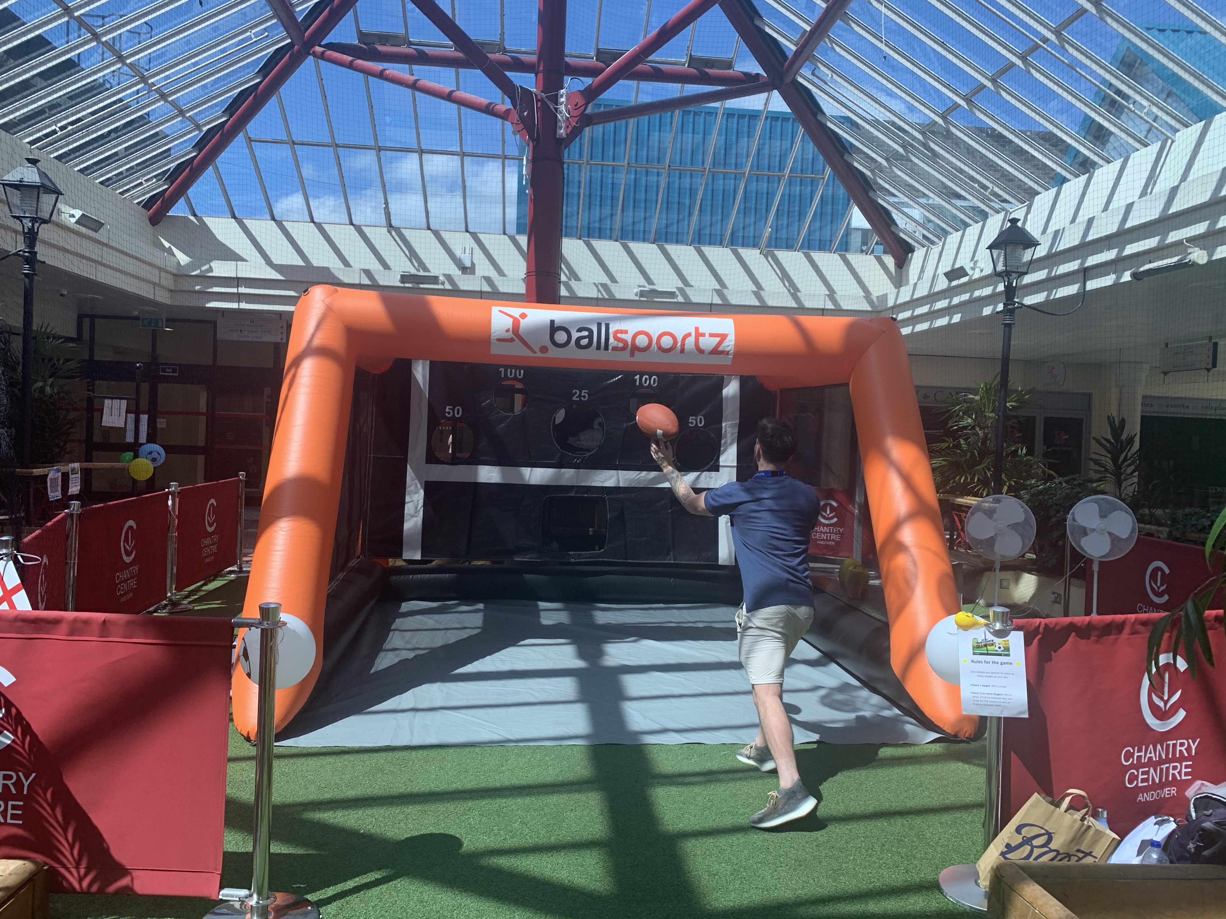 Person playing basketball arcade game inside a shopping center with a glass ceiling.