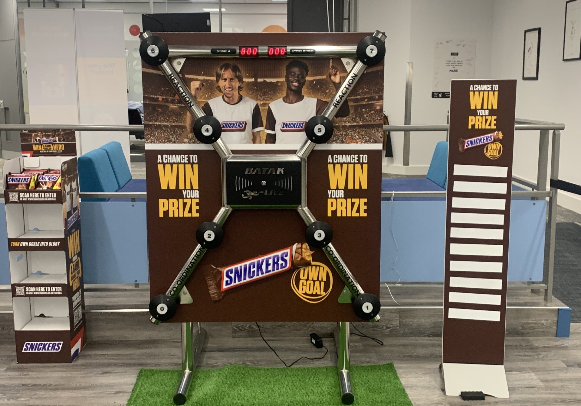 A Snickers-branded game display with buttons, score slots, and promotional prize signage.